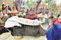 The weeping mother and villagers beside the coffin of the child.