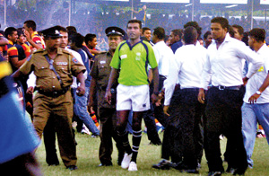 Referee Irshad Cader being escorted out of the Royal College Sports Complex field by Police personnel after the Bradby first leg last weekend. 		    - Pic by Mangala Weerasekara