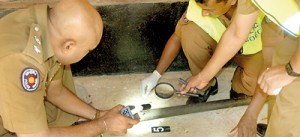 Policemen inspect the pestle that was used in the tragic death of PHI Mohammed Faleel. Pic by K.D. Wijepala