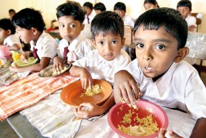 The little ones tuck into what could very well be their only meal for the day, provided by the school. Pix by M.A. Pushpa Kumara