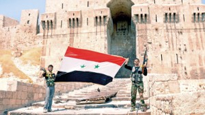 Syrian security personnel hold the national flag as they stand in front of Aleppo's historical citadel on Thursday. Reuters.