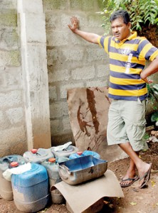 Karunarathna Sunil stands beside the contaminated fuel he had to empty from his bus. Pic by M.D. Nissanka