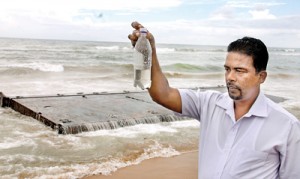 A Marine scientist testing the sea water in  Bambalapitiya. On the background is a piece from the broken ship. Pic by Indika Handuwala