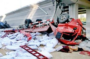 Collapse: Huge trucks lie on their side after being thrown off the Yangmingtan Bridge after it collapsed in Harbin in Heilongjiang province, north east China. The body of a driver lies next to one of the overturned trucks