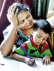 Bright-eyed Induwara draws bold flowers while Jineetha tells her tale of woe.  Pix by Athula Devapriya