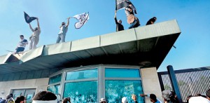 Tunisian protesters break the windows as they hold Islamic flags above the gate of US embassy in Tunis during a protest against a film mocking Islam on Friday. AFP