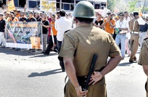Ready for action: A policeman on full alert as  protestors converge on Hyde Park in Colombo on Friday. Pic by Mangala Weerasekera
