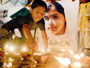 A Pakistani youth places an oil lamp next to a photograph of child activist Malala Yousafzai, who was shot in the head in a Taliban assassination attempt, as he pays tribute in Karachi on October 12 (AFP)