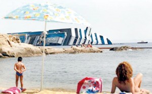 Vacationers in front of the wreckage of capsized cruise liner Costa Concordia near  Giglio Porto harbour (REUTERS)