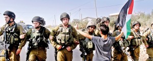 A palestinian protester holds a national flag as he stands in front of Israeli soldiers during a protest against Israel's controversial separation barrier in the West Bank village of Maasarah near Bethlehem on October 19, 2012 as they mark the sixth anniversary of the start of weekly demonstrations against the wall (AFP pic/Musal al-Shaer)