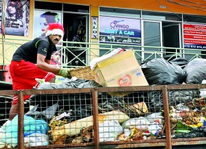 Even municipal workers have got into the Christmas spirit. Here a worker wearing a Santa hat and matching shorts lays out garbage on a truck at Nawala. Pic by Amila Prabodha