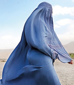 An Afghan burqa clad pedestrian walks as a girl looks on in the old city of Herat (AFP)