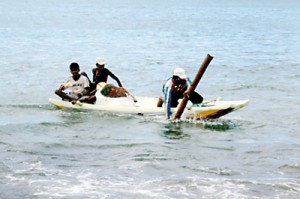 A group of men bring  their boat ashore