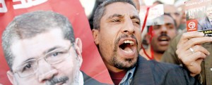 Members of Egypt's Muslim Brotherhood and other supporters of President Mohammed Morsi (portrait) shout slogans during a rally outside a mosque in Cairo in support of a deeply disputed constitutional referendum proposed by the Islamist president (AFP)