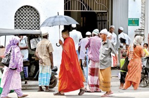 Unity in diversity: In the backdrop of some incidents of tension in recent weeks, a Buddhist monk passes a mosque while a group of the Muslim faithful look on. Pic by Mangala Weerasekera.
