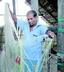A fisherman holds up a net  damaged by Indian trawlers