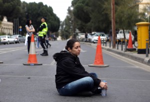 A Cyprus bank employee sits on the ground as protesters blocked the streets leading to the parliament in Nicosia.  AFP