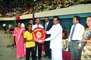 Minister of Education, Bandula Gunawardena, presenting the Overall Challenge Shield to the captain of the champion D. S. Senanayake College gymnastics team.
