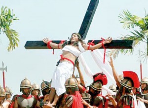 Ruben Enaje, 52, who is portraying Jesus Christ for the 27th time, is raised on a wooden cross by a group of men playing Roman soldiers after he was nailed to it during a Good Friday crucifixion re-enactment (REUTERS)