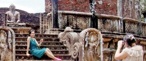 A tourist poses with her back to a statute of the Buddha