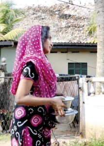 A resident carries food, in the background the big stench looms large. Pix by Indika Handuwala