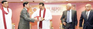 Economy doing well: Central Bank Governor Nivard Cabraal formally hands over the Central Bank Annual report 2012 to President Rajapaksa