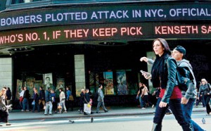 People walk by news ticker announcing on April 25, 2013, that bombers in the Boston marathon were plotting attacks on New York City's Times Square in New York (AFP/Emmanuel Dunand)