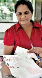 Old reading, new reading? A housewife in Colombo looks on with trepidation as the metre reader came knocking at her door last morning. Pix by Indika Handuwala