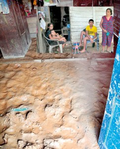 Razline and her family (incet) wait outside their humble abode that was filled with flood waters and mud