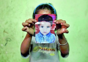 Mansi, 7, poses with a photograph of her missing three-year-old sister, Muskaan, inside their house in New Delhi (REUTERS)