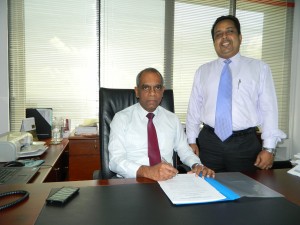 Picture shows Director/CEO of Pan Asia Bank Claude Peiris signing the agreement on behalf of the bank, flanked by Richie Dias, DGM-Treasury”