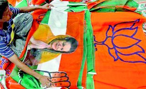 A worker looks at a Congress party flag carrying a picture of its party chief Sonia Gandhi next to flags of main opposition Bharatiya Janata Party (BJP) inside an election campaigning material workshop on the outskirts of Ahmedabad (Reuters)