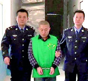 Journalist Chen Yongzhou, in handcuffs, is escorted by police officers at the Changsha Public Security Bureau detention centre in Changsha City (Reuters)