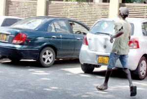 A hooligan  rushes up to collect 'his due' as a motoristprepares to leave from a designated parking area