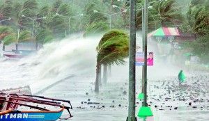 A resident (R) walks past high waves pounding the sea wall amidst strong winds as Typhoon Haiyan hit the city of Legaspi, Albay province, south of Manila on Friday. AFP