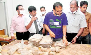 Custom officials inspect the packets of heroin found in the cans of grease (below) that arrived in a consignment from Pakistan