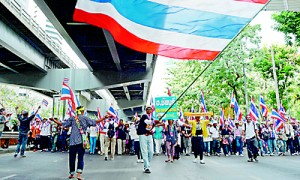 Thai anti-government protesters wave national flags as they march through the streets of Bangkok as part of their ongoing rally on December 20 (AFP)