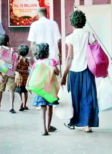 Food for thought: An impoverished family walks home on New Year's Day with donations from a benefactor. In front of them is a board advertising a supermarket chain's Christmas giveaways to customers