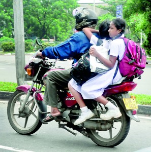 At risk to life and limb parents are forced to take two or more children on the pillion of their bikes.