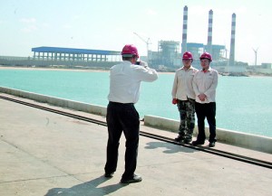 Cheese: Chinese workers snap a picture with the power station as backdrop