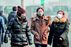 A group of women wear face masks as they make their way along a street  in Beijing on January 16.  China's capital was shrouded in thick smog, cutting visibility down to a few hundred metres as a count of small particulate pollution reached more than 20 times recommended levels. AFP