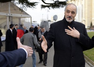 Syria's permanent representative at the United Nations Bashar al-Jaafari extends his hand to a journalist as he speaks to the press before a meeting at the “Geneva II” peace talks (AFP)