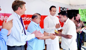 Picture shows Philippe Richart, Holcim Lanka CEO; Gunarathne Weerakoon, Minister for Resettlement and Dr. Ramesh Pathirana, MP, Galle District presenting recipients their home ownership deeds.