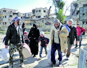 Civilians carry their belongings as they walk towards a meeting point to be evacuated from a besieged area of Homs (Reuters)