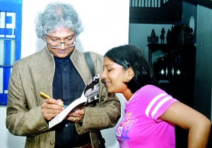 Romesh Gunesekera autographs his book for a young reader at the launch at Barefoot. Pix by Nilan Maligaspe