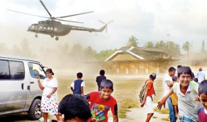 Children and adults alike flee to avoid the 'dust storm' raised by an incoming helicopter