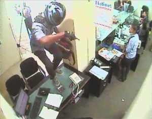 A CCTV grab shows the armed robber wearing full-face helmet jumping over a desk prior to removing the cash from the drawyers at the Kohuwala Nations Trust Bank