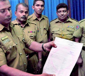 Police officers hold up a forged certificate of registration (inset). Pix by Mangala Weerasekera