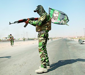 A fighter from the Shi'ite Badr Brigade militia wears a religious flag as he guards a checkpoint outside the town of Amerli