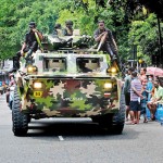 Slave Island - Three-fold: An APC moves between a petrol queue and a gas queue